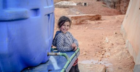 happy poor girl near huge reservoir with water